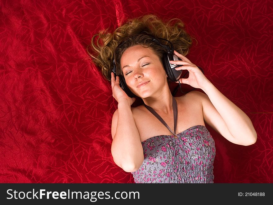 Cute girl with headphones on red bed. Cute girl with headphones on red bed