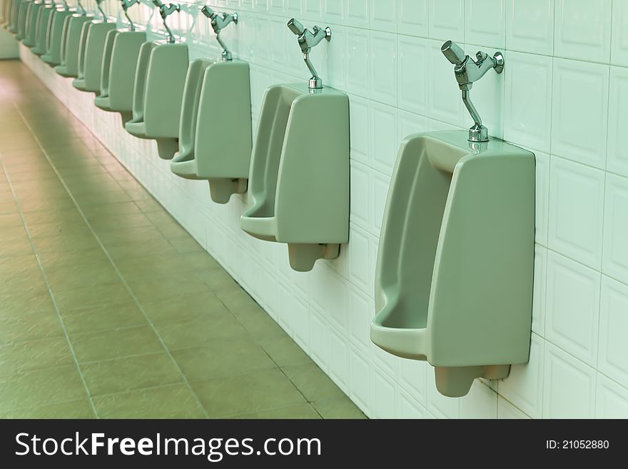 A row of urinals in tiled wall in a public restroom