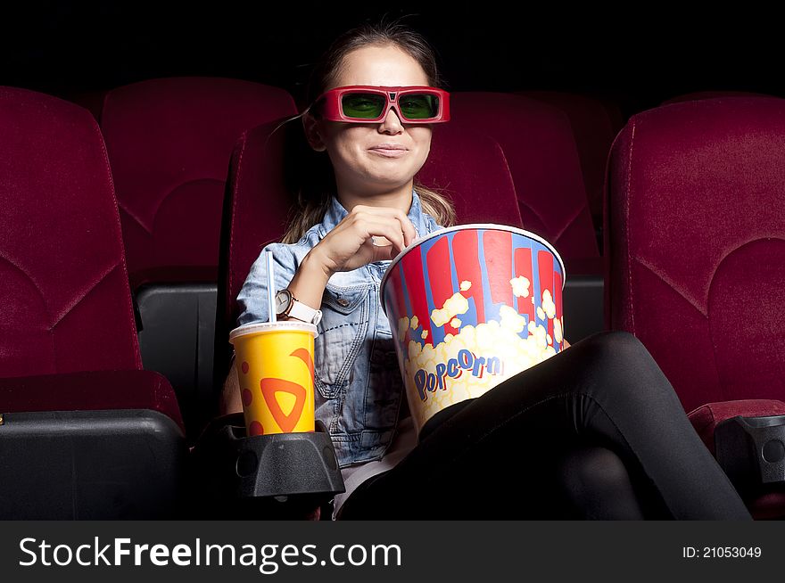 Young woman sitting alone in the cinema and watching a movie. Young woman sitting alone in the cinema and watching a movie