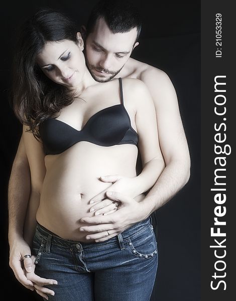 Happy pregnant women and father on black background caressing the belly with sweetness and love. Happy pregnant women and father on black background caressing the belly with sweetness and love