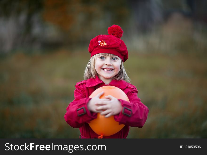 Smilling girl, wears in a red cap and red coat, with orange balloon. Smilling girl, wears in a red cap and red coat, with orange balloon