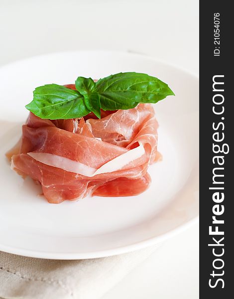 Slices of fresh prosciutto with a leaf of basil. Slices of fresh prosciutto with a leaf of basil