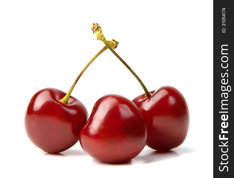 Three red ripe cherries lie on a white background. Three red ripe cherries lie on a white background