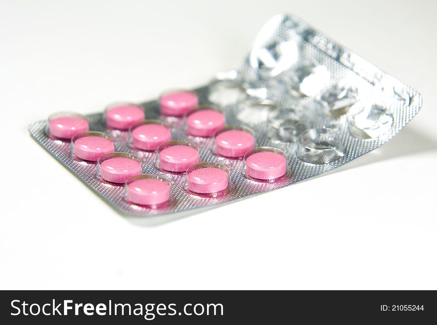 Package of pink tablets on white background