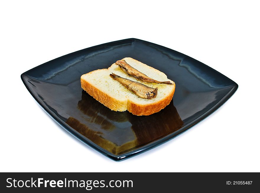 Square black plate with bread and sprats. Isolated on white background