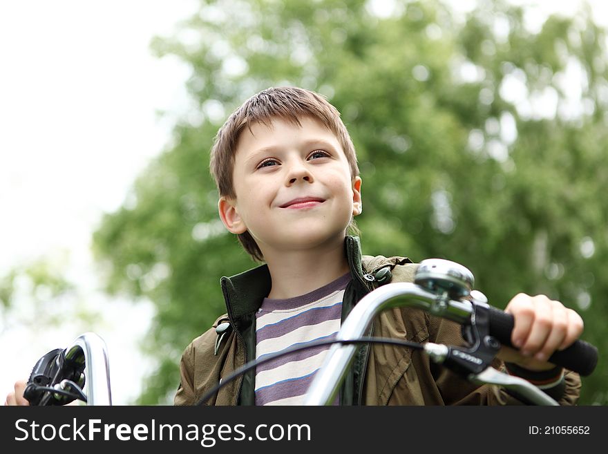 Happy smiling boy on a bicycle in the green park