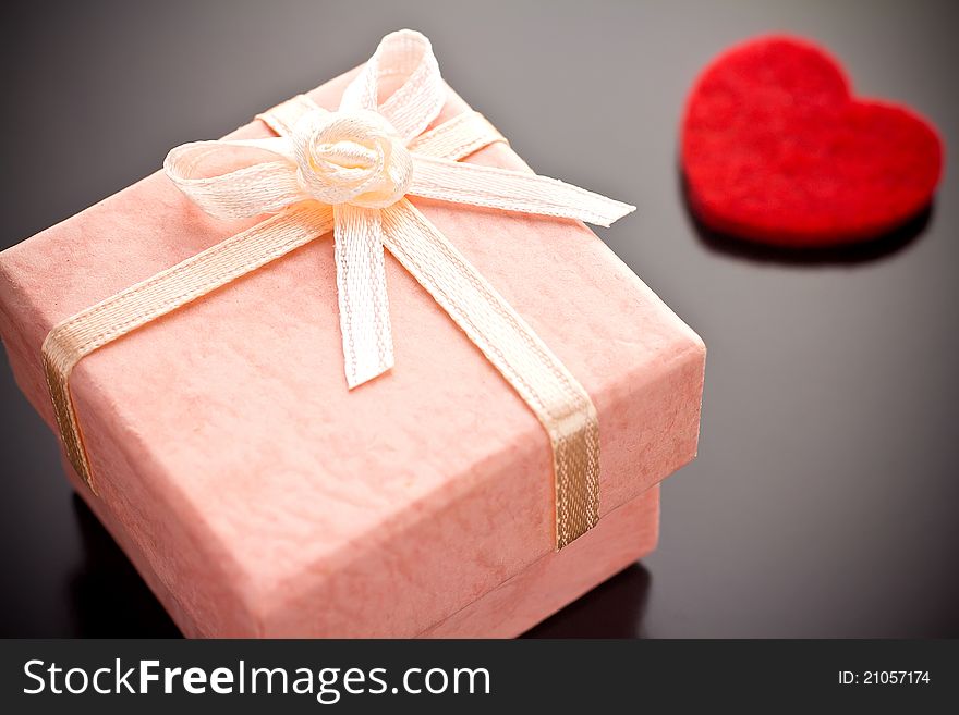 Pink gift box with a red heart on a gray background. Pink gift box with a red heart on a gray background.