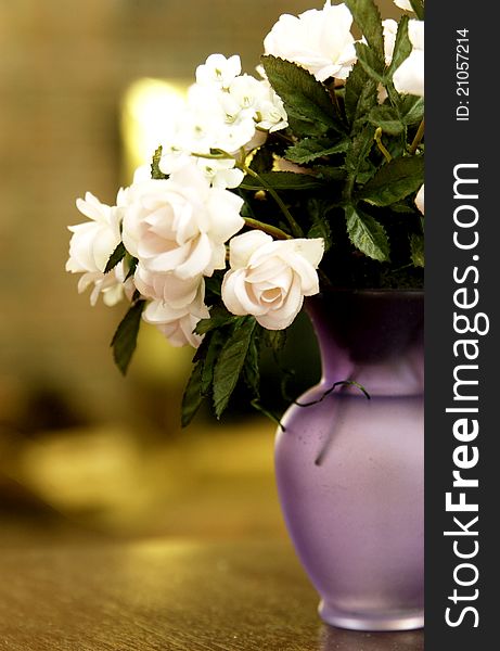 Silk flowers sitting in purple vase on table. Silk flowers sitting in purple vase on table