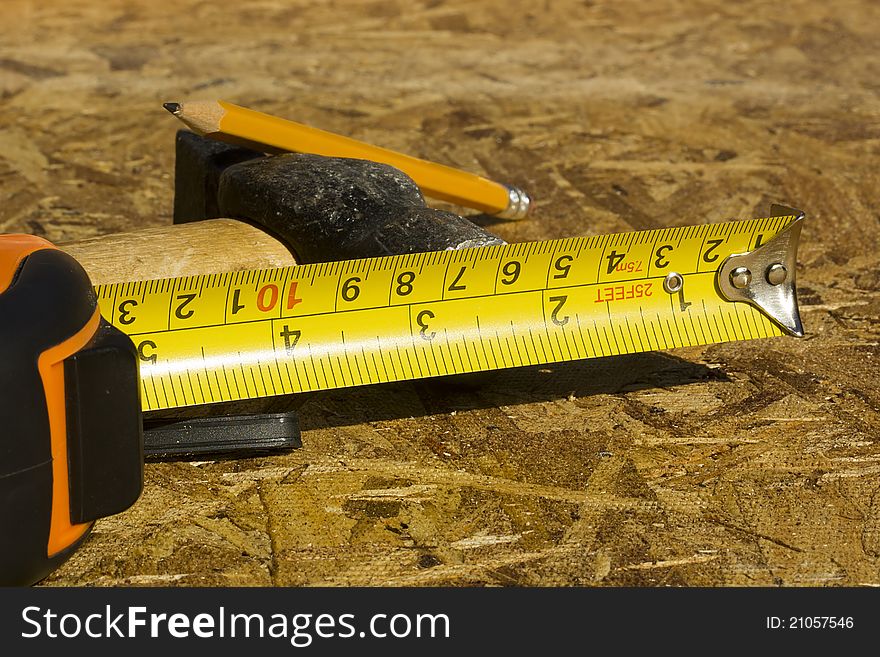 Measuring tape and other construction tools in the background on plywood. Measuring tape and other construction tools in the background on plywood.