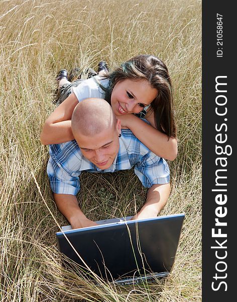 Happy boy and girl sitting on the grass and use a netbook on the Internet. Happy boy and girl sitting on the grass and use a netbook on the Internet