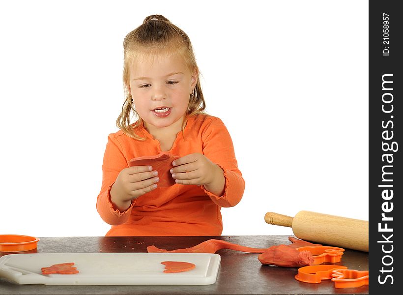 A cute preschooler making Halloween cutouts using modeling clay, a rolling pin and cookie cutters. A cute preschooler making Halloween cutouts using modeling clay, a rolling pin and cookie cutters.