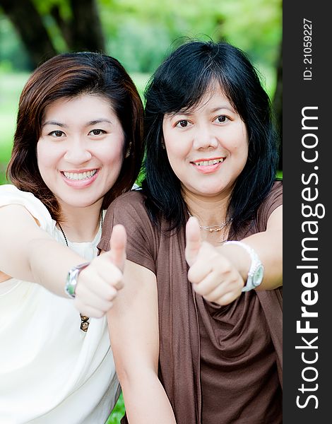 Portrait of two asian women giving thump up