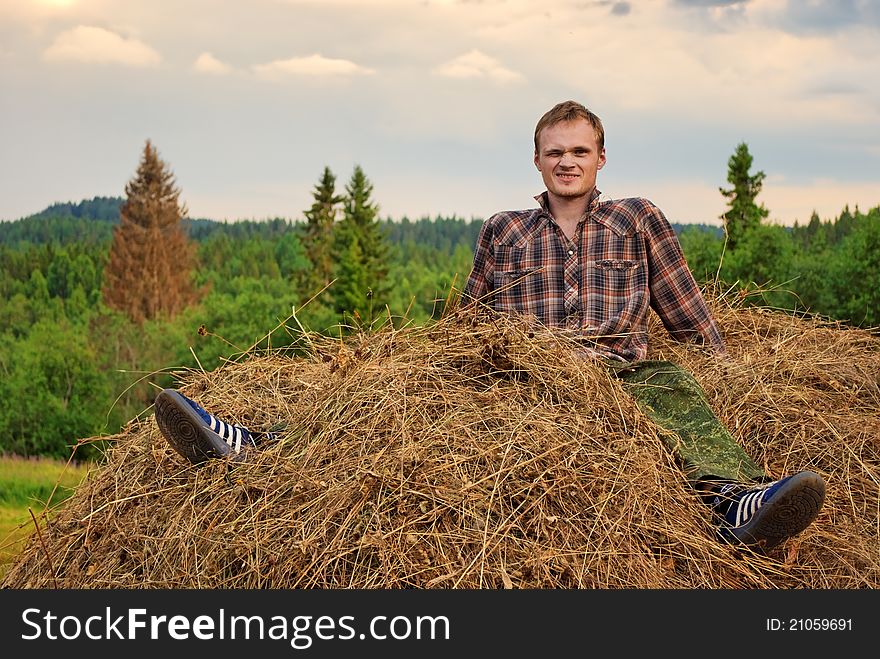 Young man astride hay stack. Young man astride hay stack