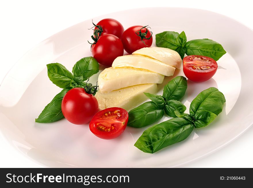 Mozzarella cherry tomatoes basil on a white plate