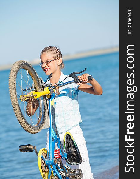 Beautiful young girl standing with her bicycle. the background sea