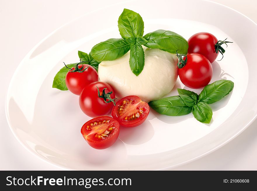 Mozzarella cherry tomatoes basil on a white plate