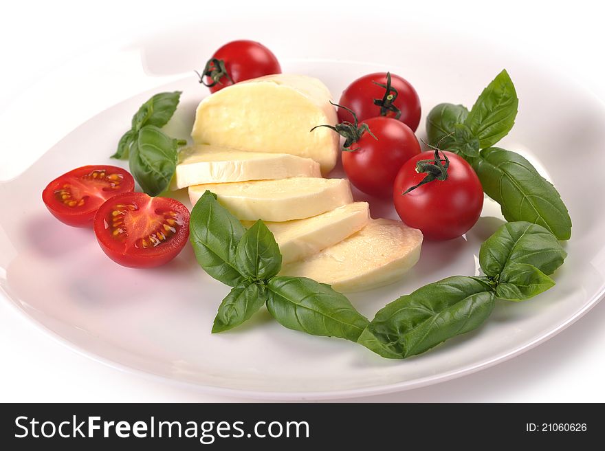 Mozzarella cherry tomatoes basil on a white plate