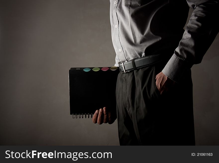 Person holding office spiral diary over gray background. Person holding office spiral diary over gray background