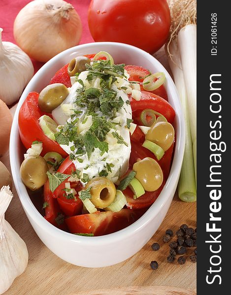 Mediterranean tomato salad with olives and garlic in a white bowl