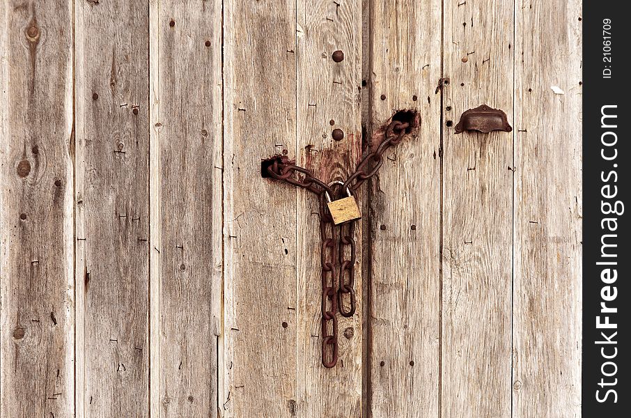 An old wooden door closed with a chain. An old wooden door closed with a chain