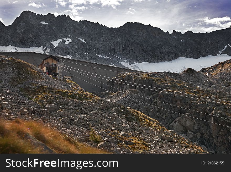 Dam and man-made lake between mountains. Itâ€™s Venerocolo Lake, North of Italy, Lombardy region, at 2.540 meters on the sea-level. In front the cableway. Dam and man-made lake between mountains. Itâ€™s Venerocolo Lake, North of Italy, Lombardy region, at 2.540 meters on the sea-level. In front the cableway