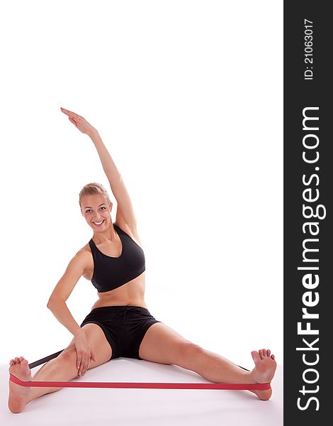 A young beautiful woman is doing exercises with a red stretch band. A young beautiful woman is doing exercises with a red stretch band