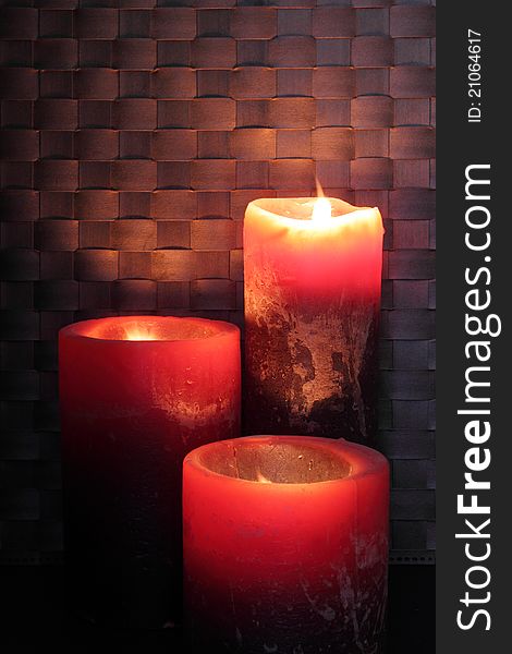 Three lighted candles on dark background