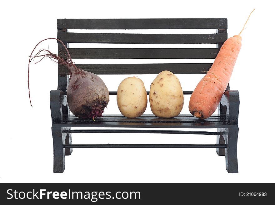 Potato, carrots and beet are spread out on a bench in the form of a family. Potato, carrots and beet are spread out on a bench in the form of a family
