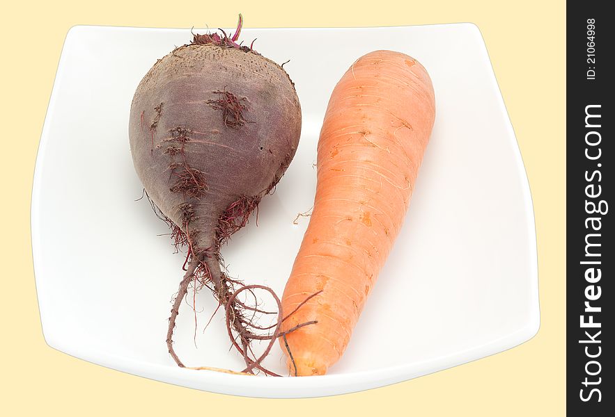 Crude carrots and beet in a plate it is isolated a close up. Crude carrots and beet in a plate it is isolated a close up