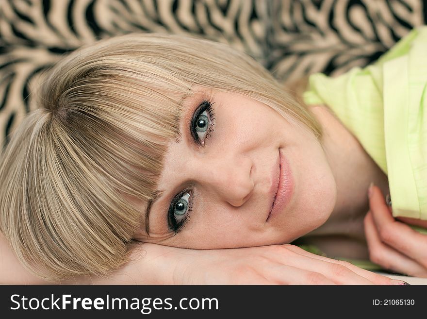 Girl's face lying on a sofa close up on a striped background. Girl's face lying on a sofa close up on a striped background