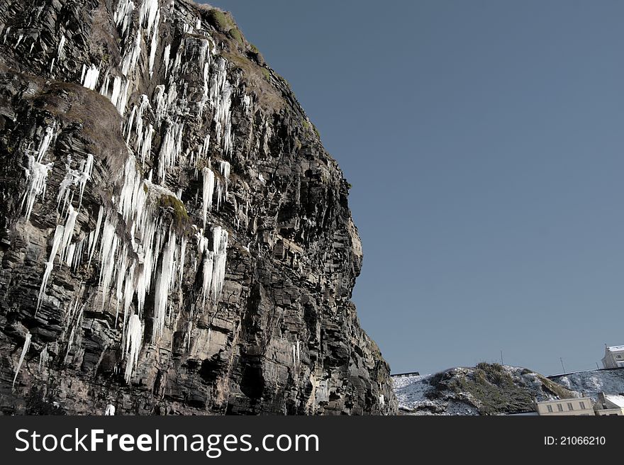 Cascade of icicles thaw on a cliff face