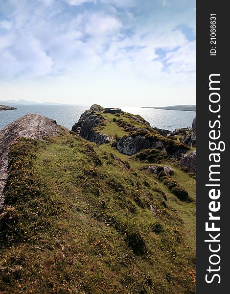 Scenic view in kerry ireland of rocks and sea with mountains against a beautiful bright sunny sky. Scenic view in kerry ireland of rocks and sea with mountains against a beautiful bright sunny sky