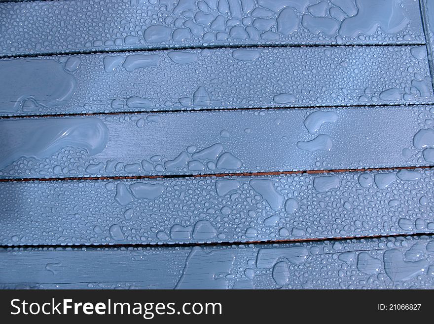 A wooden garden chair with rain drops on the surface. A wooden garden chair with rain drops on the surface