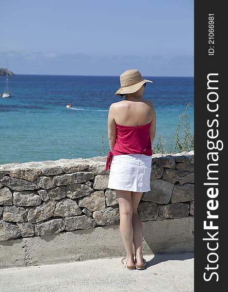 A woman in a straw hat looking out to sea.