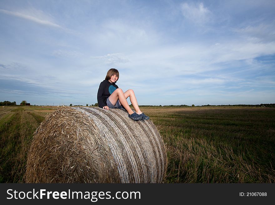 A boy sitting on huge bales of hay. A boy sitting on huge bales of hay