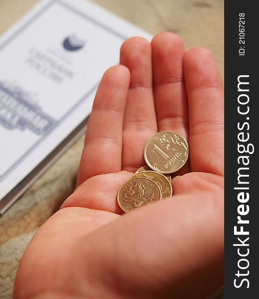 Small coins in the palm on the background of the credit book