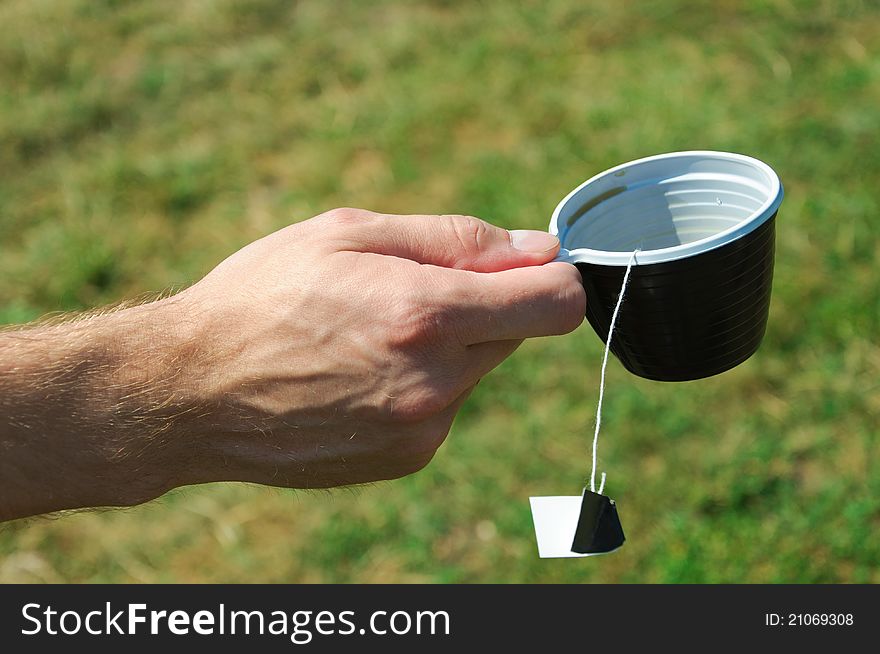 Teabag on a plastic cup on green background