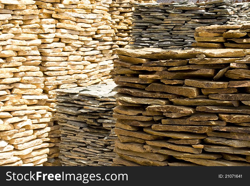 Large stacks of golden and cream colored rock slabs. Large stacks of golden and cream colored rock slabs.