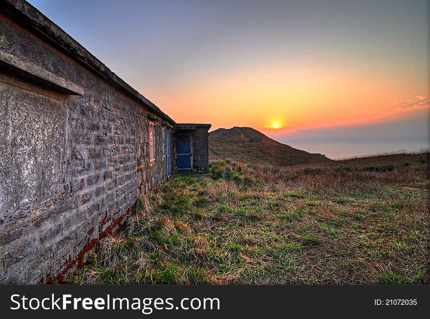 Beautiful sunrise at Sunset Peak, the third highest mountain in Hong Kong, in Lantau Island. The building is an abandoned camp hut.