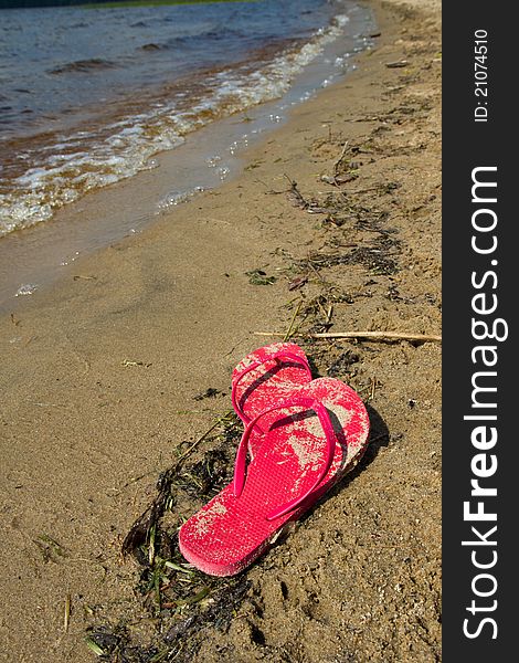 Red flip flops abandoned along a lakeside beach. Red flip flops abandoned along a lakeside beach