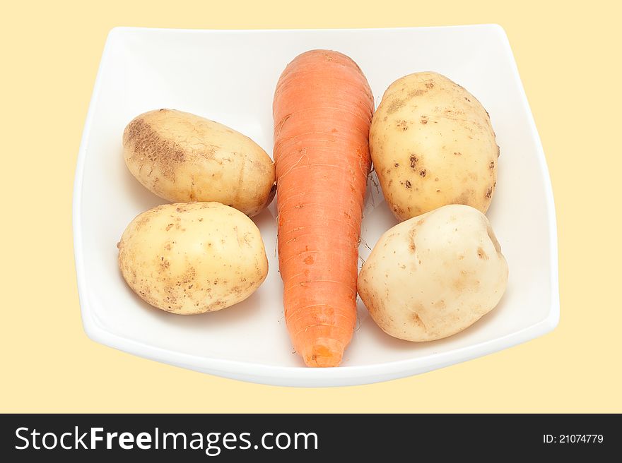 Carrots and potato on a white plate close up it is isolated