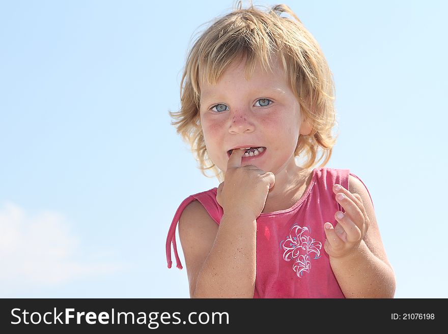 Cute young girl with finger in mouth over sky background