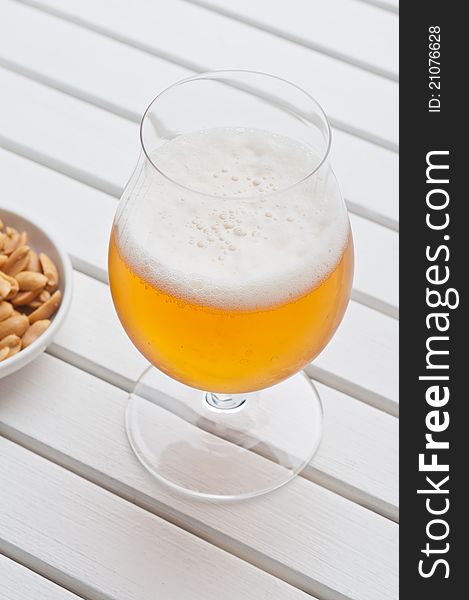 Beer with peanuts on a white table