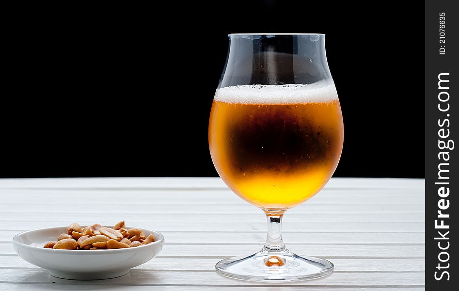 Beer with peanuts on white table