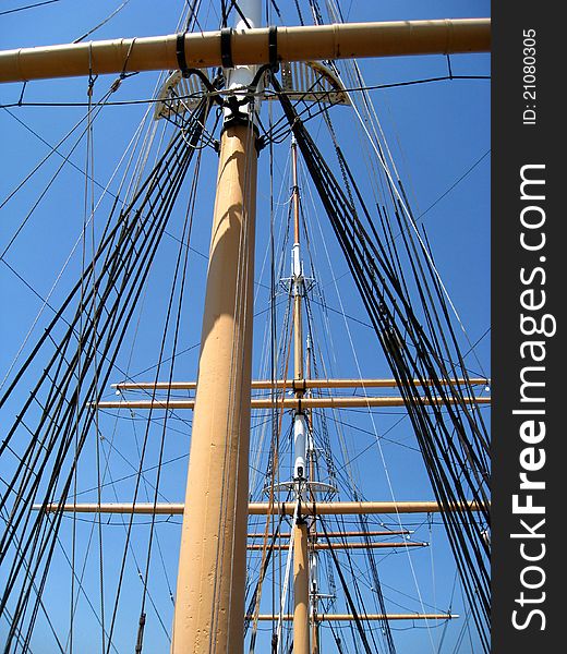 Closeup upshot of large sailboat mast and rigging set in front of a bright blue couldless sky. Closeup upshot of large sailboat mast and rigging set in front of a bright blue couldless sky.