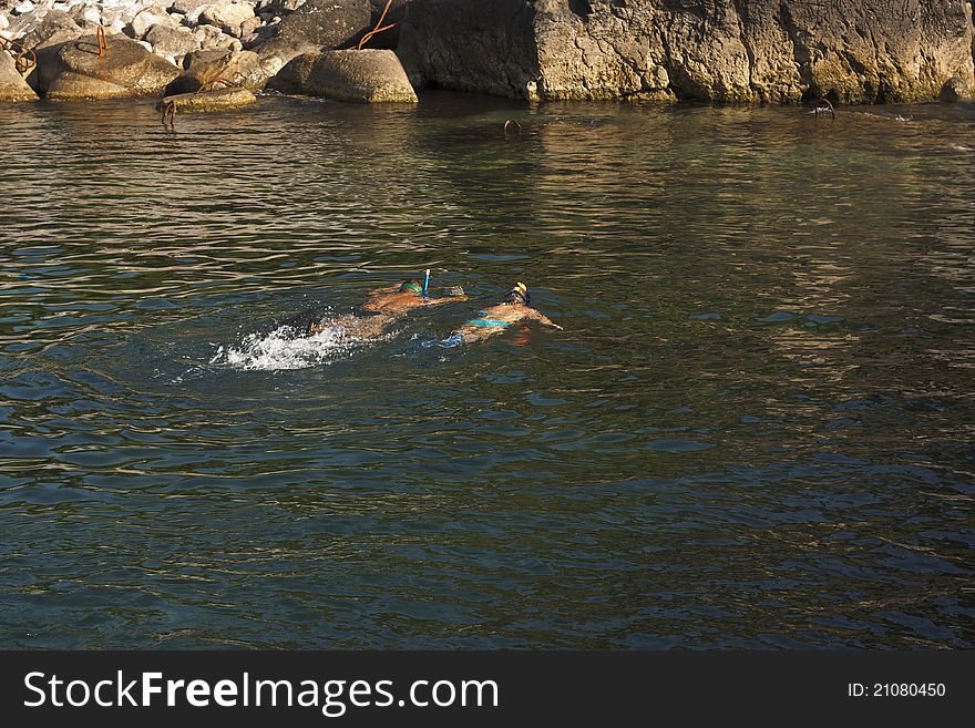 Snorkellers swim in the coastal rocks and stones