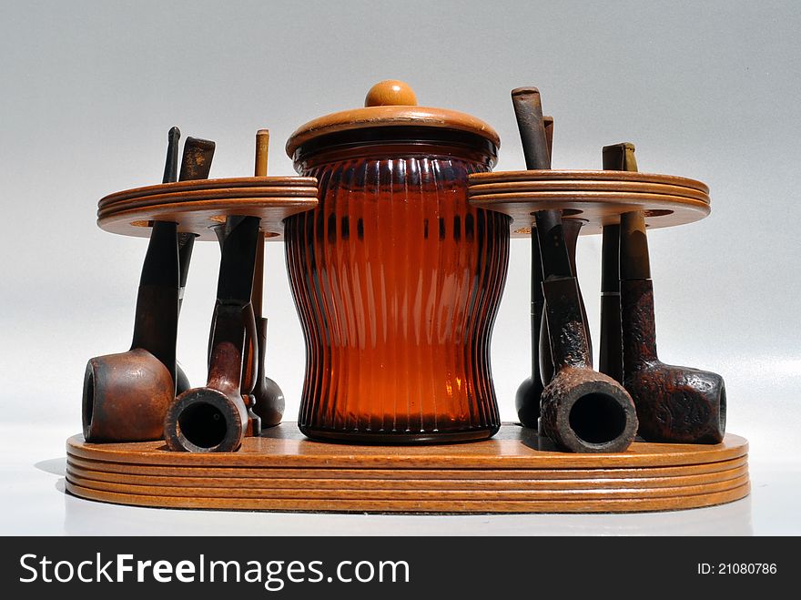 Vintage pipe collection in wood stand with brown glass tobacco jar / humidor. Vintage pipe collection in wood stand with brown glass tobacco jar / humidor