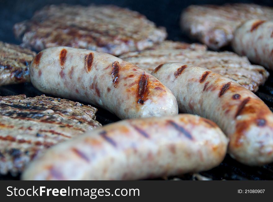 Bratwursts and hamburgers cooking on the grill. Bratwursts and hamburgers cooking on the grill.