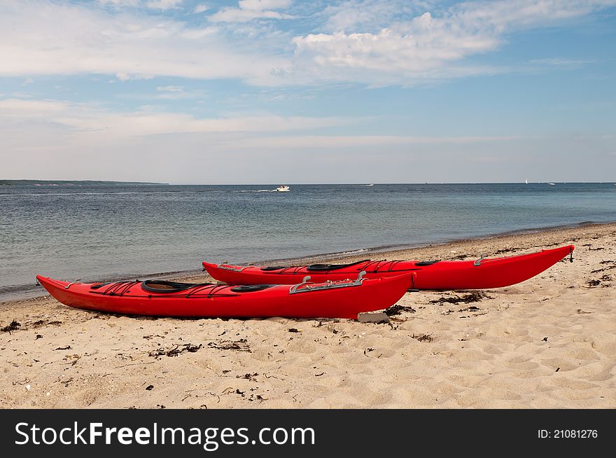 Two red sea kayaks placed in the sand