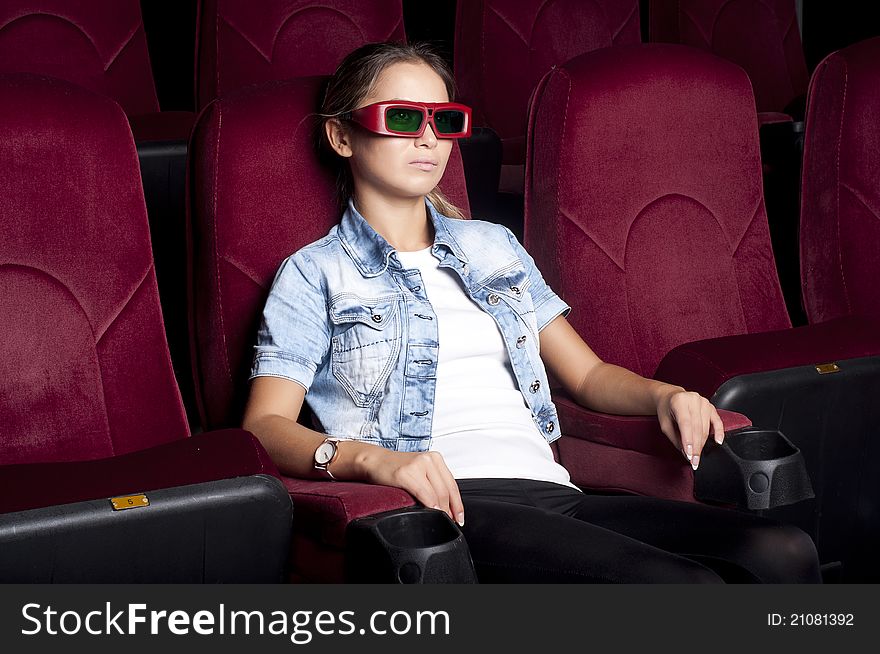 Young woman sitting alone in the cinema and watching a movie. Young woman sitting alone in the cinema and watching a movie